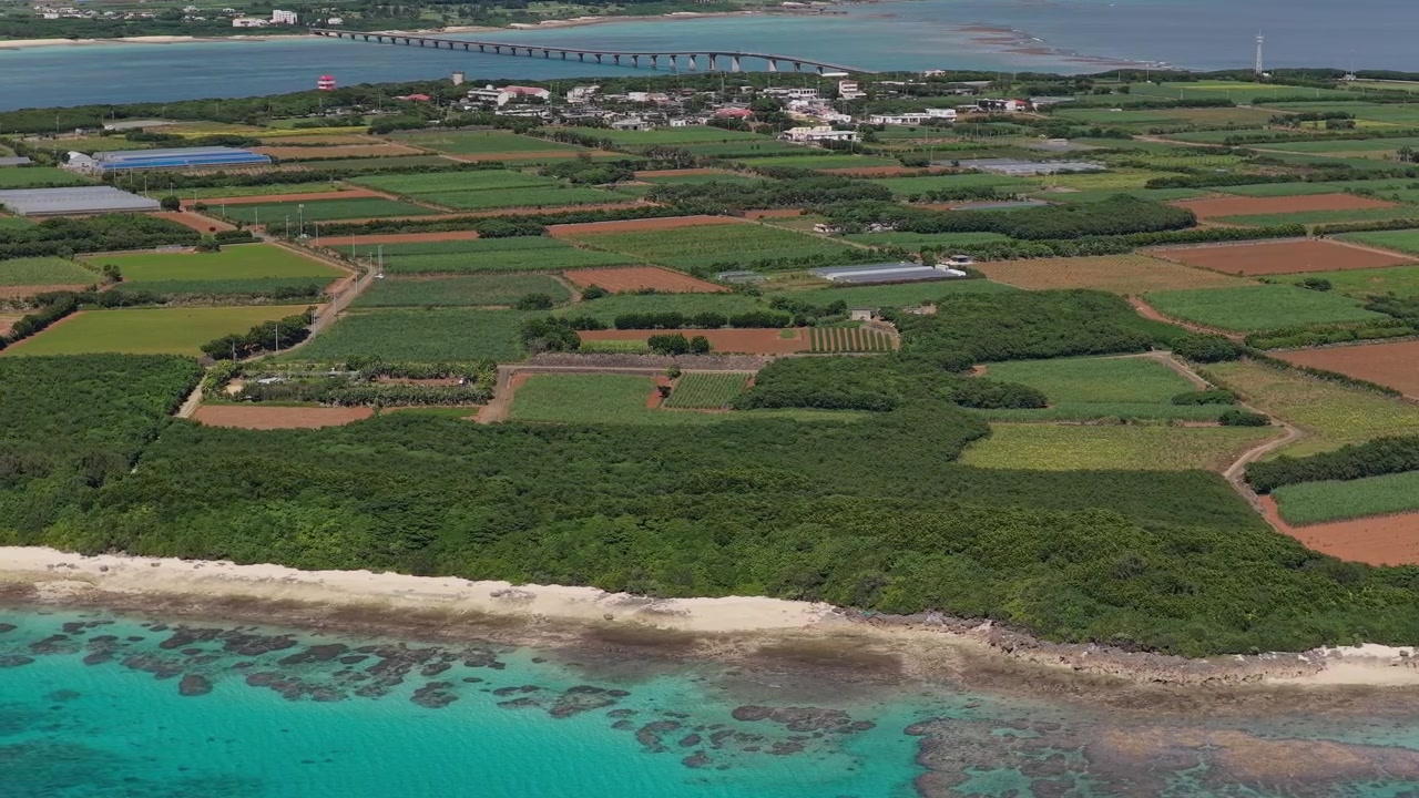 Horisontale luftoptagelser, der panorerer til højre, mens de bevæger sig til venstre over Musunun Strand, kystlandbruget og kystlinjen på Kurima Ø, Miyakojima, Okinawa, Japan