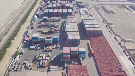 reveal of a very large container yard with colorful containers and highways on either side in the desert