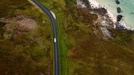 a white car drives along a coastal road near keen beach in ireland along the wild atlantic way