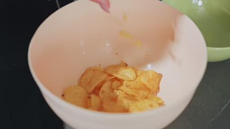 close up of pringles chips falling into bowl on kitchen counter, crispy snack food, golden fried potato chips, casual home cooking, crunchy tasty treat, snack preparation