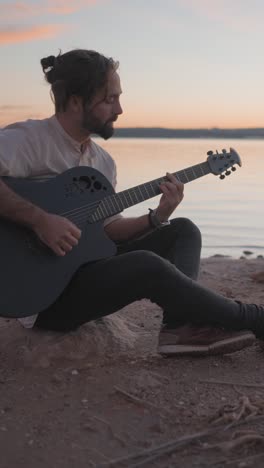Man Playing Guitar by the Water at Sunset