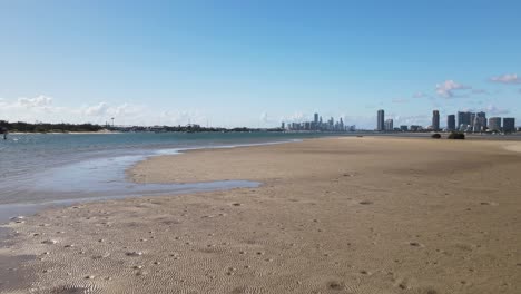 fast revealing view of a natural sand island with a city skyline in the distance