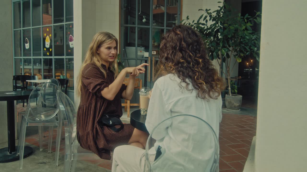 Two Women Enjoying Conversation in a Cafe Patio