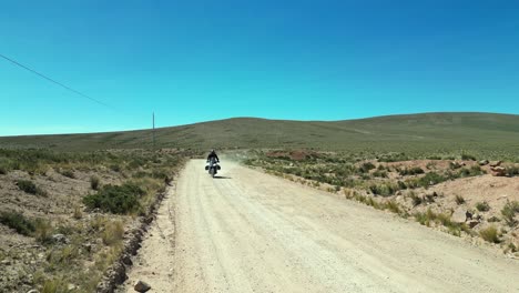 lone motorcycle rides toward camera in arid, remote peru landscape