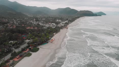 Imágenes-Laterales-De-Drones-De-La-Playa,-Montaña-Y-Casas-Frente-Al-Mar,-Día-Nublado,-Olas,-Paisaje-De-Juquehy,-Ubatuba,-Costa-Norte-De-São-Paulo,-Brasil