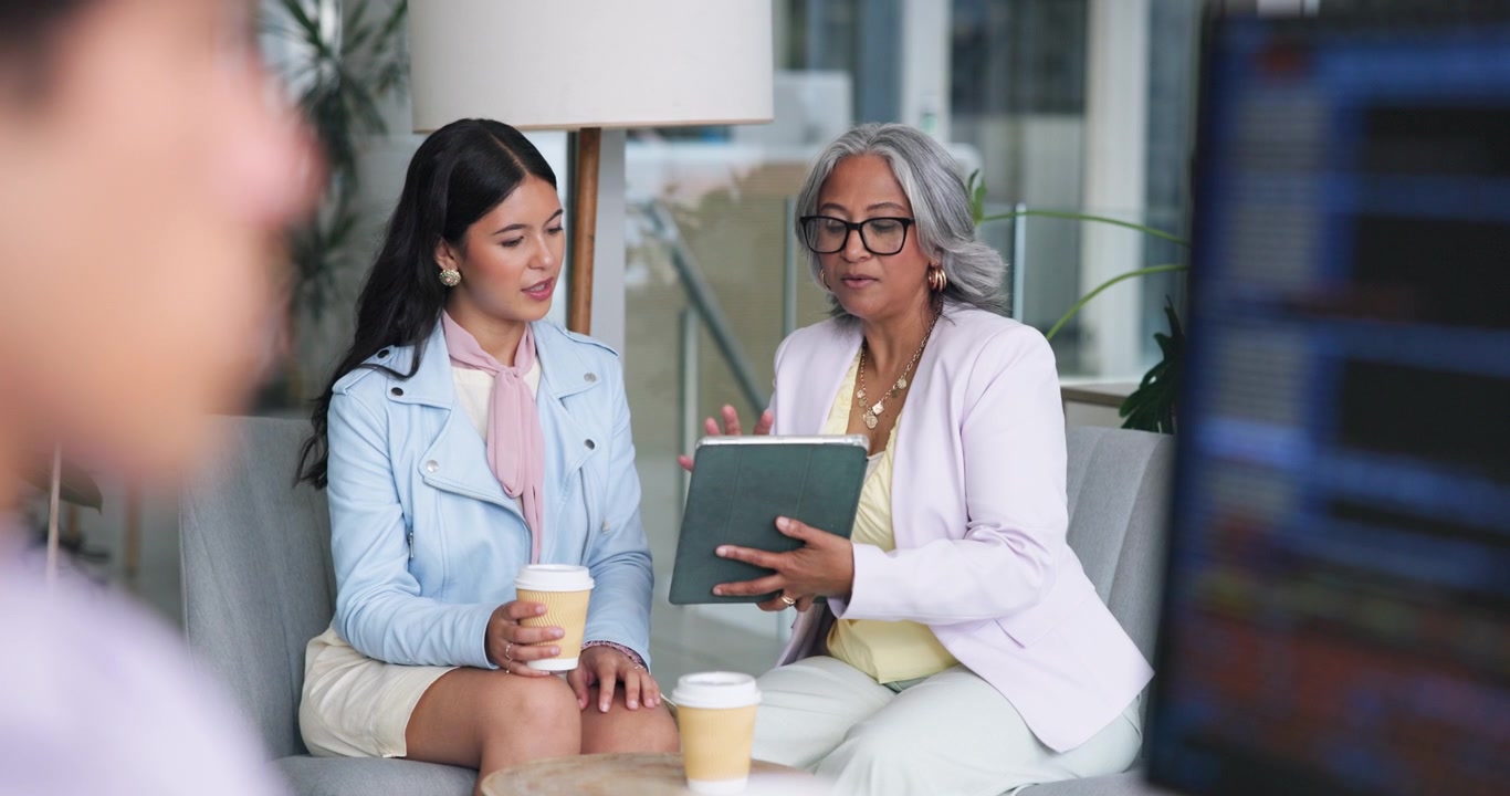 Two Businesswomen Discussing Work on a Tablet in an Office