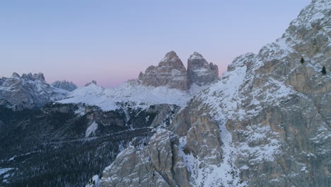 Snowy-extreme-rugged-Tre-Cime-mountain-slope-aerial-view-towards-South-Tyrol-mountainous-landscape