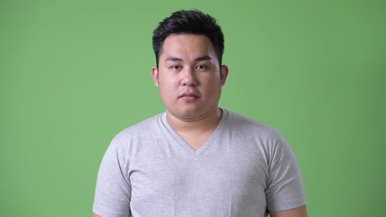 초록색 배경에 젊은 잘생긴 과체중 아시아인