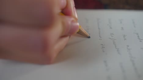 close-up of hands writing on a white sheet of paper sentences in spanish