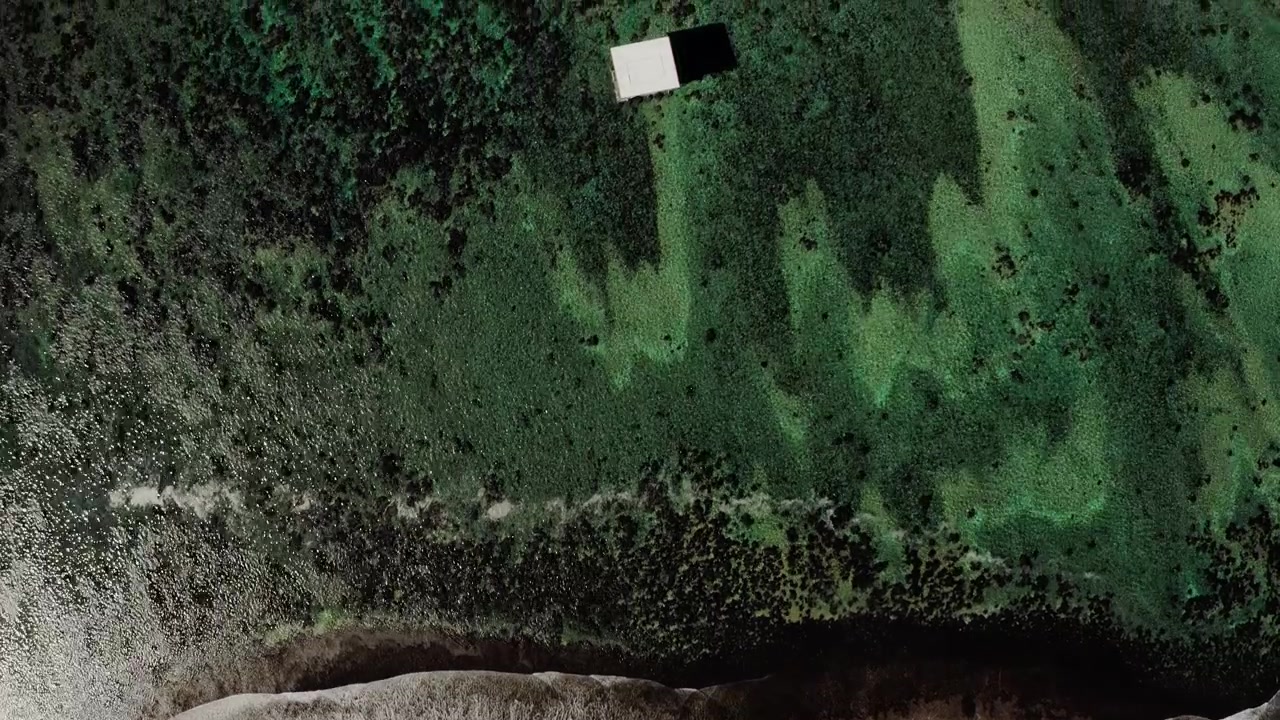Drohnenaufnahme von oben: Tiefes, offenes Pazifikwasser vor Teahupoo, Tahiti, mit dunkler, welliger Textur und schwachem Licht, das sich auf der Oberfläche spiegelt.