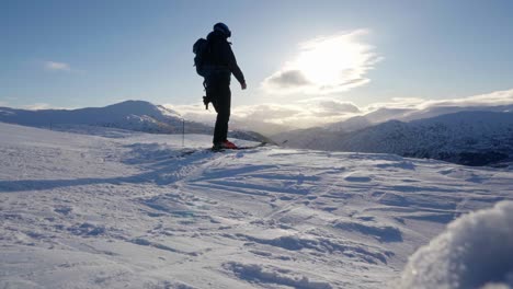 Sunset-silhouette-of-person-on-top-of-mountain,-prepare-to-ski-down