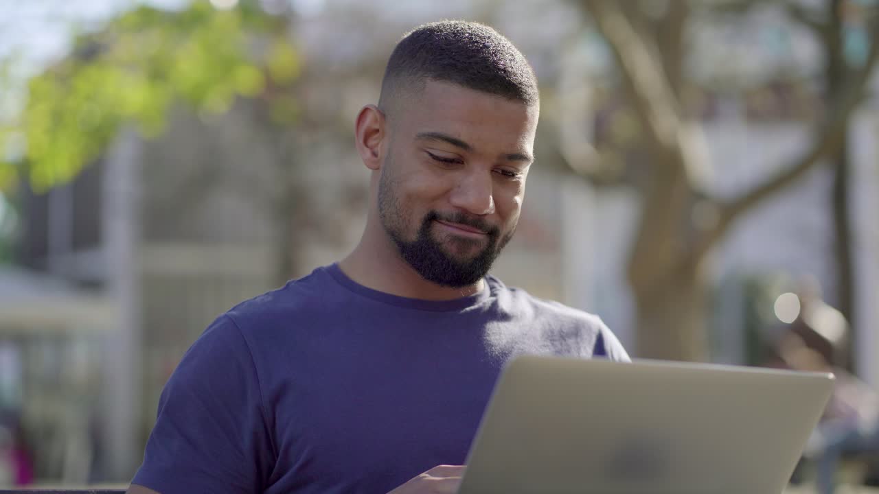 Man working on laptop in park, thinking, behaving emotionally