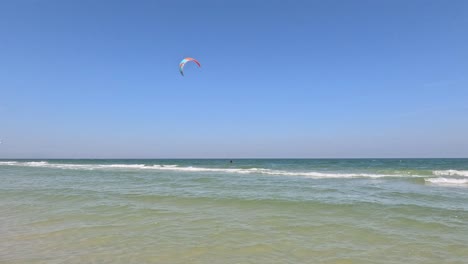 kite surfer gliding over ocean waves near beach