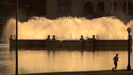Man-running-against-a-background-of-water-fountain-and-lake