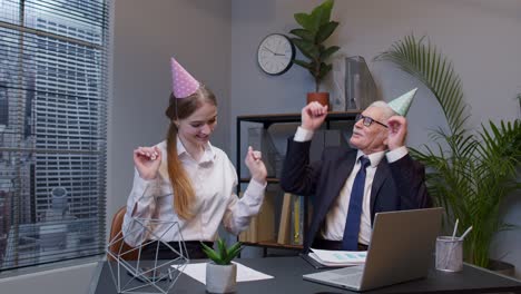 two joyful collegues in formal suits dancing victory dance, celebrating success of business project