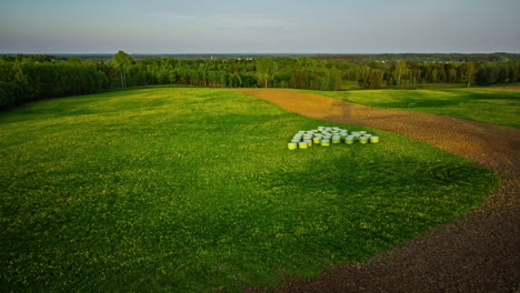 Aerial-time-lapse-shot-of-agricultural-fields-surrounded-by-forest-during-sunny-day--Shadow-of-transmission-tower-on-green-grass-during-daytime