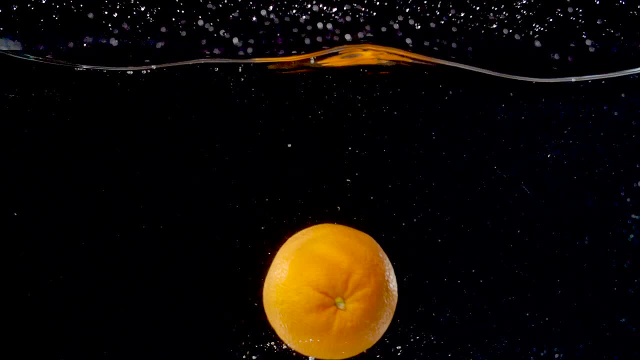 Arancia dai colori vivaci lasciata cadere nell'acqua al rallentatore