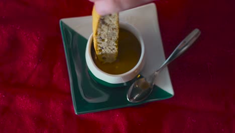 a woman dips a biscotti stick into an expresso cup