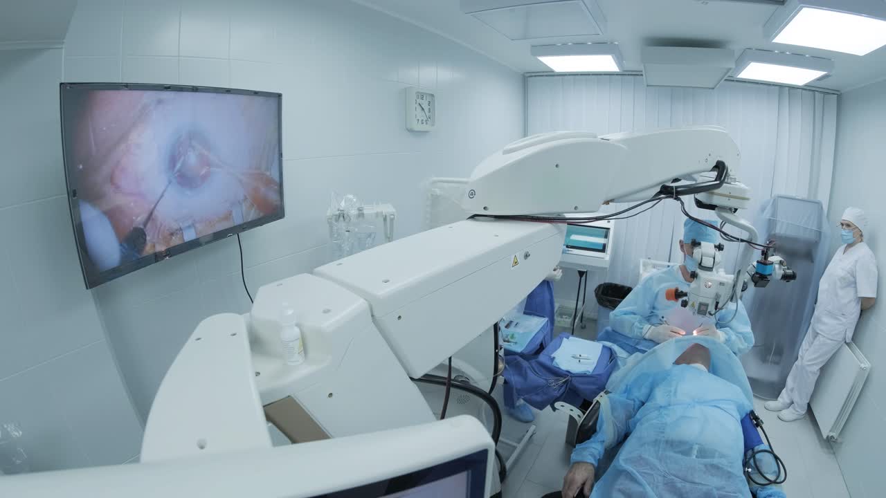 cirujano mirando al microscopio en el ojo de la paciente femenina en la sala de operaciones. médico usando el microscopio durante el proceso de cirugía ocular, tratamiento de cataratas y corrección de dioptría.