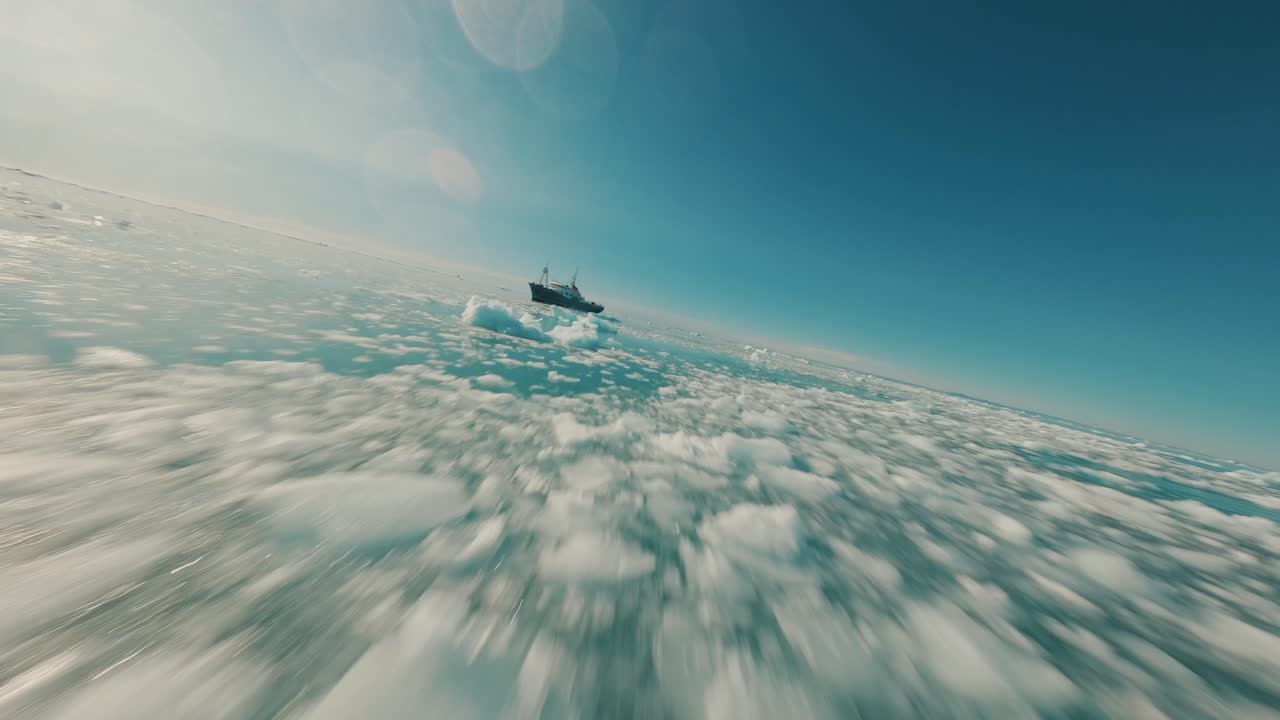 Drone FPV che vola sul ghiaccio marino artico verso una nave nelle acque delle Svalbard.