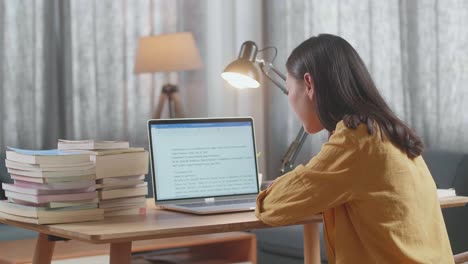 mujer estudiando en casa con computadora portátil y libros