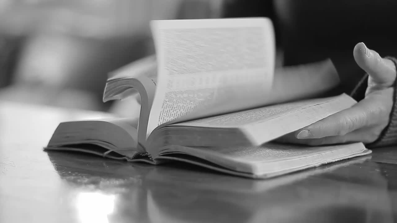 Close-up of hands interacting with an open book, possibly reading or in contemplation