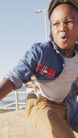 video of happy african american father learning son how to skateboard on promenade