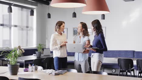 Diverse-female-colleagues-in-discussion-using-laptop-in-casual-office-meeting,-slow-motion