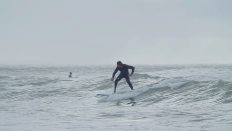 hombre deportivo en traje de neopreno con pierna artificial surfeando en el océano 1