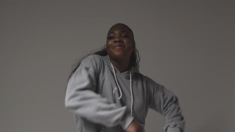 portrait en studio d'une jeune femme portant une capuche dansant avec un éclairage bas sur un fond gris 5