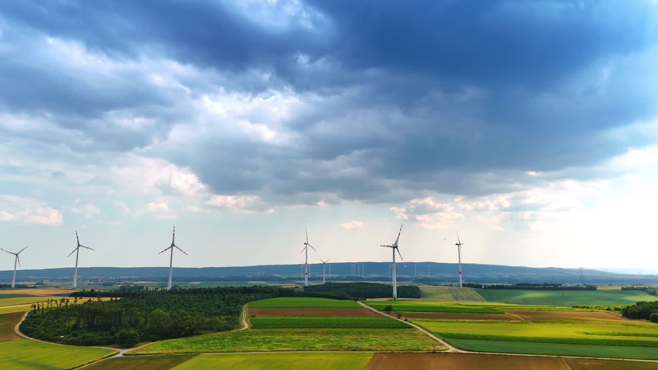 Wind turbines produce rural energy. Wind turbines stand tall in a vast rural landscape under a cloudy sky, representing sustainable energy production