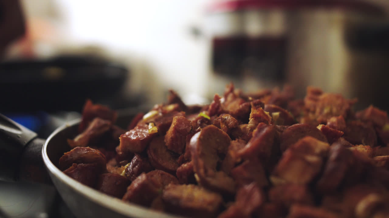 Close-up of a frying pan with cooked pork in pieces giving off smoke