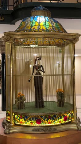 elegant catrina skeleton sculpture displayed inside a golden cage with stained glass detail