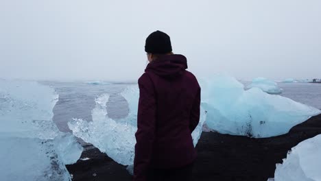 Verfolgen-Sie-Die-Aufnahme-Eines-Touristen,-Der-Durch-Eisberge-Am-Diamond-Beach-In-Südisland-Spazieren-Geht