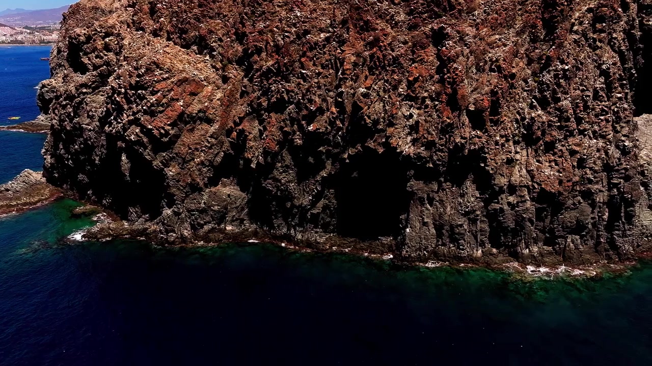 Kanarya Adaları, Tenerife'deki Punta del Bocinegro'da okyanusla buluşan dik volkanik kayalıkların havadan drone çekimi. Engebeli kıyı jeolojisi ve uzak Atlantik vahşi doğası.