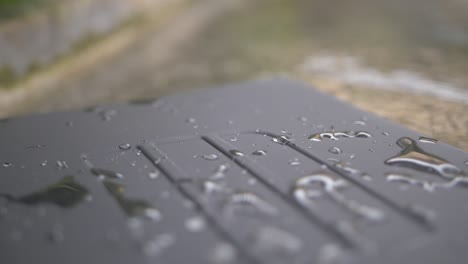 a slow motion shot of a waterproof laptop case sitting on the side of a pool with water splashing around and a few drops on top of the plastic surface