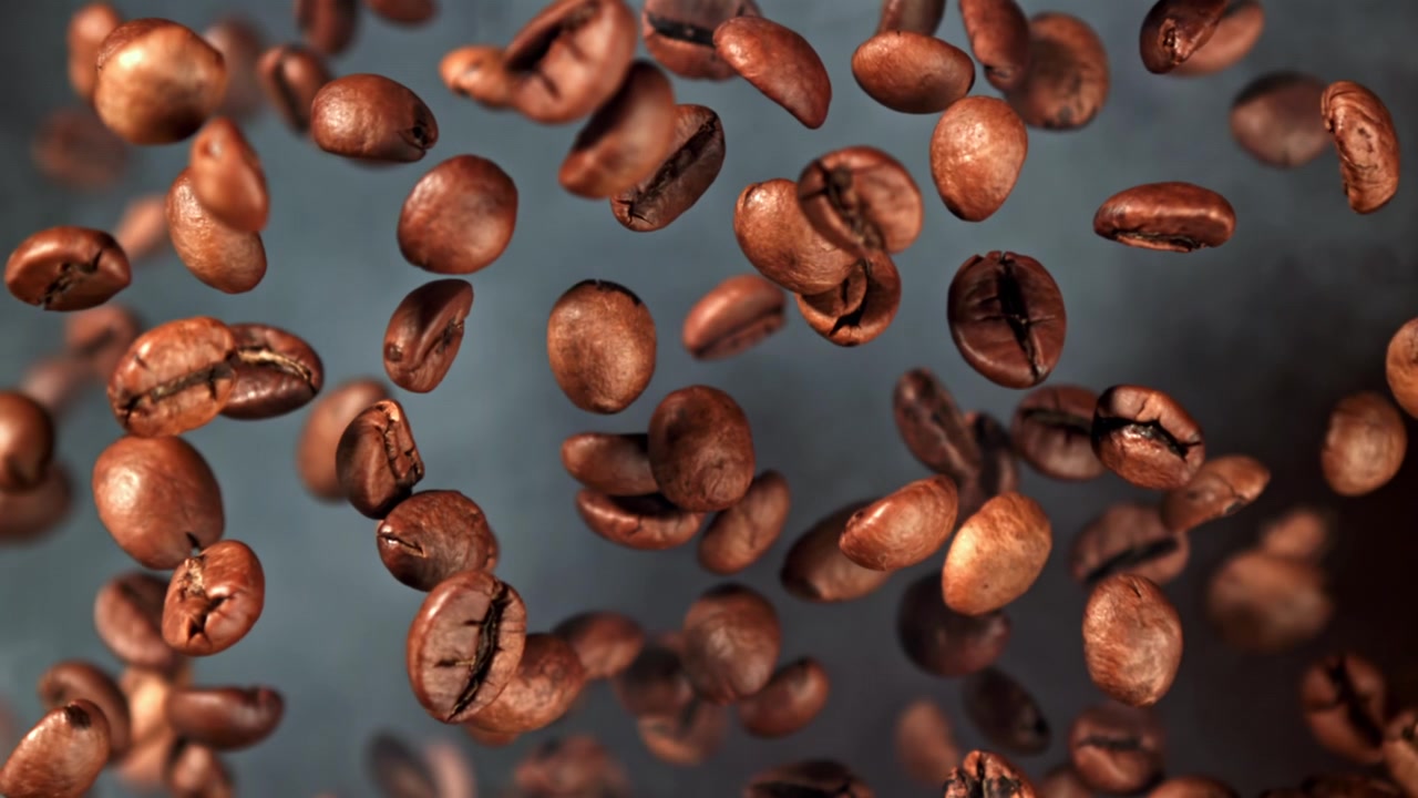 Chicchi di caffè tostati che cadono al rallentatore con fumo
