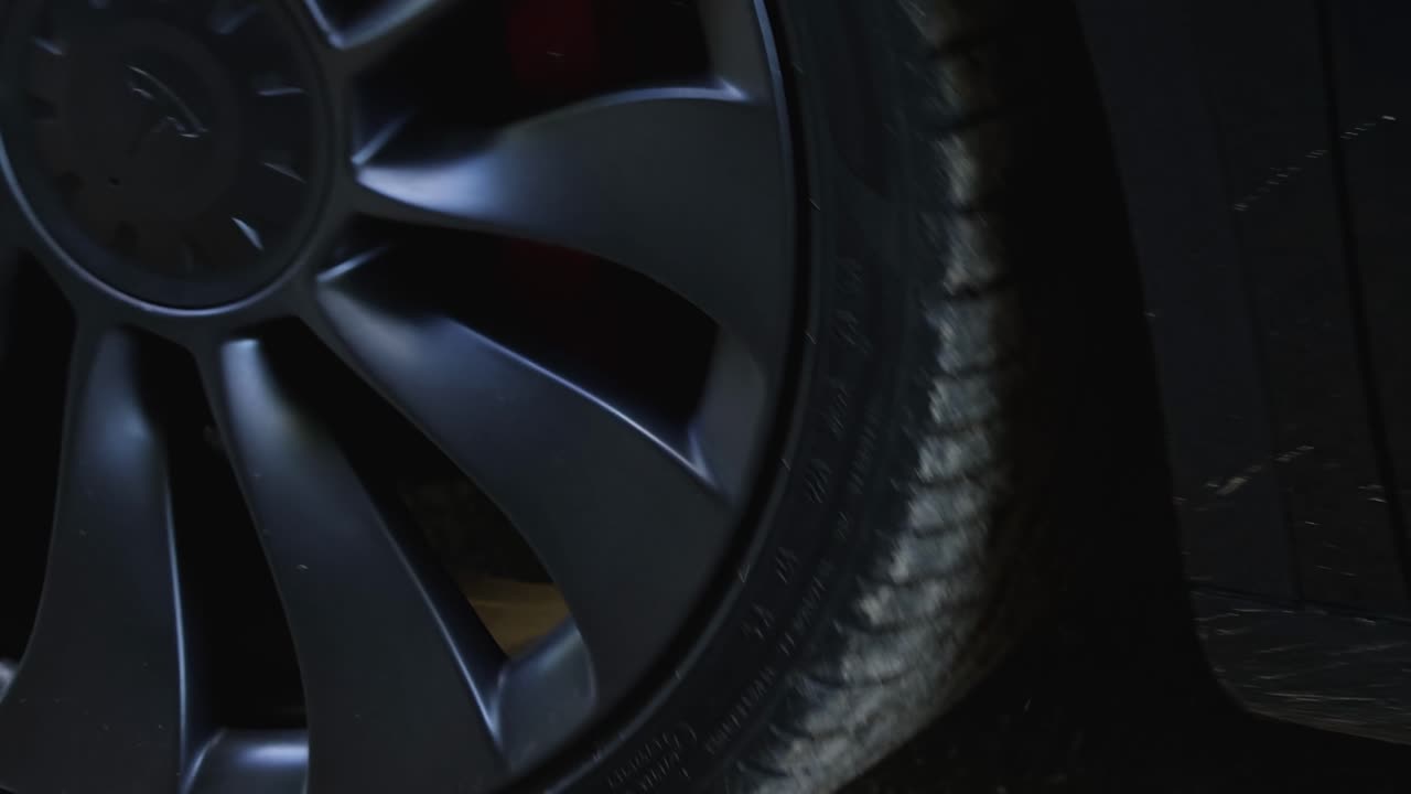 Detailed view of black car wheels and tires on a gravel surface, showcasing design and texture.