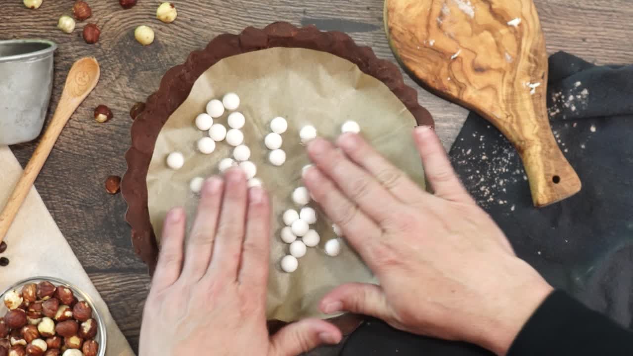 A delicious dessert, Coffee Hazelnut Cream Tart. Made with espresso powder, chocolate crust and loaded with crushed hazelnut. Adding white pie weights to the chocolate crust using hands