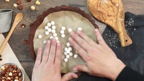 a delicious dessert, coffee hazelnut cream tart. made with espresso powder, chocolate crust and loaded with crushed hazelnut. adding white pie weights to the chocolate crust using hands