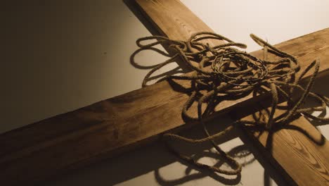 religious concept shot with crown of thorns being thrown onto rope and wooden cross in pool of light