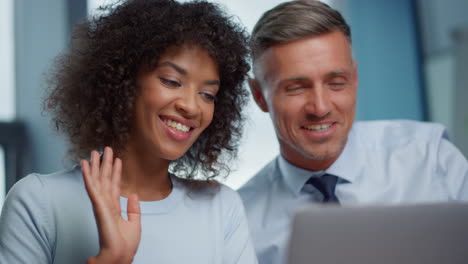 businessman and businesswoman waving hands hi at camera during online video call