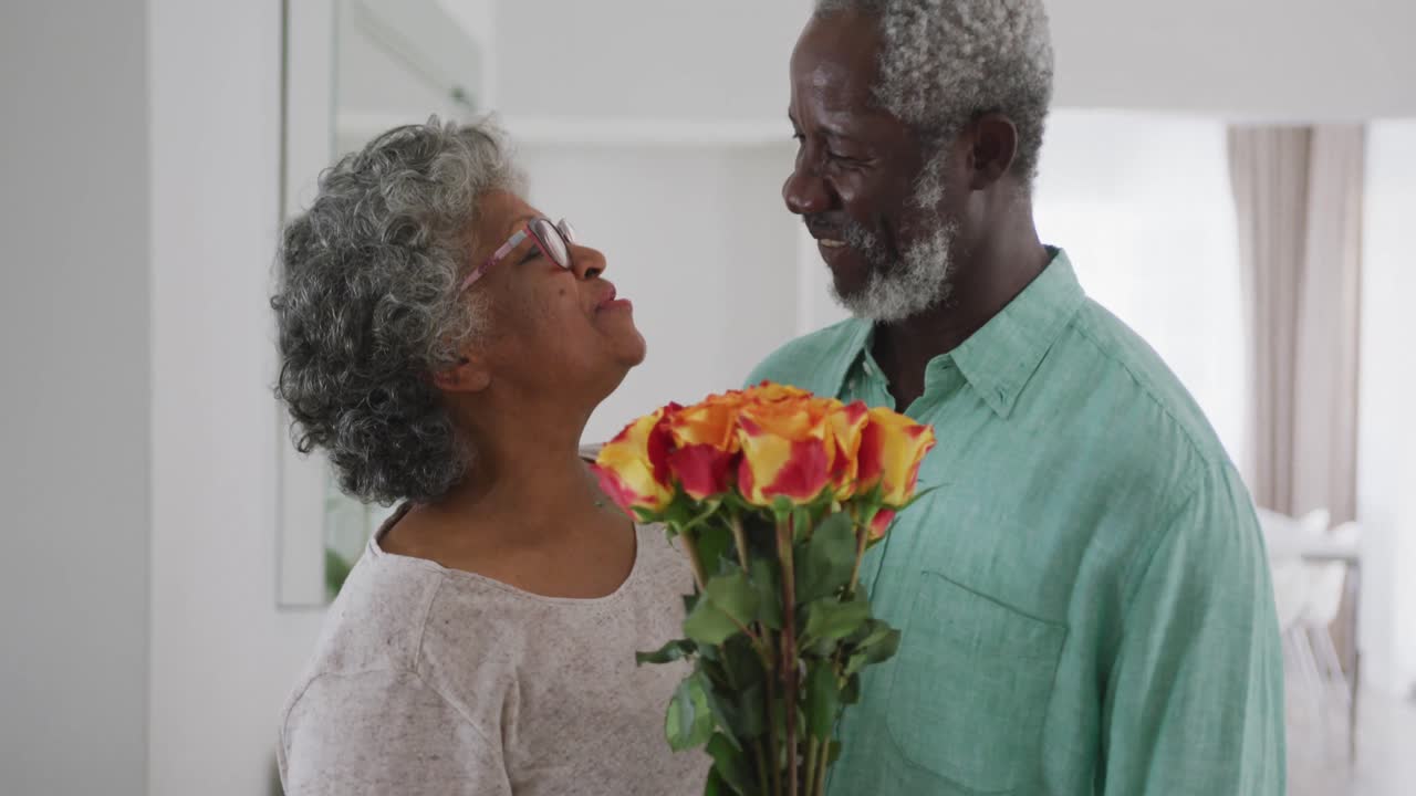 A senior African American man offering flowers to his wife