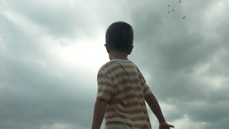 a young boy looking up at the sky in slow motion, his eyes full of wonder and curiosity watching clouds. this cinematic footage captures the innocence and imagination of childhood.