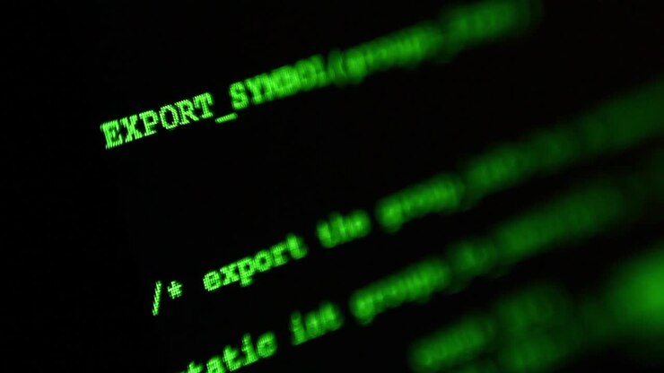 Inquadratura macro o ravvicinata di un display di monitor a schermo nero con codici di programmazione verdi casuali che continuano ad apparire.