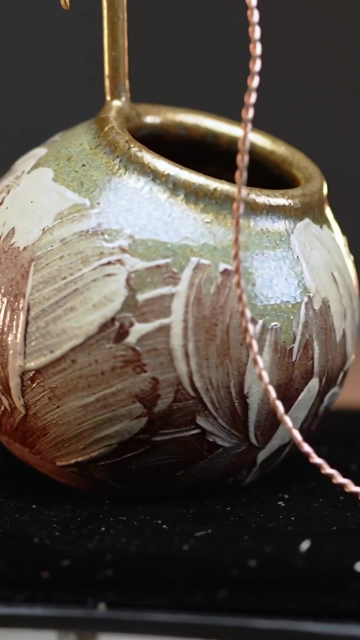 Vertical video: Panning camera revealing green pot on black pad, showing brushwork, brass rod