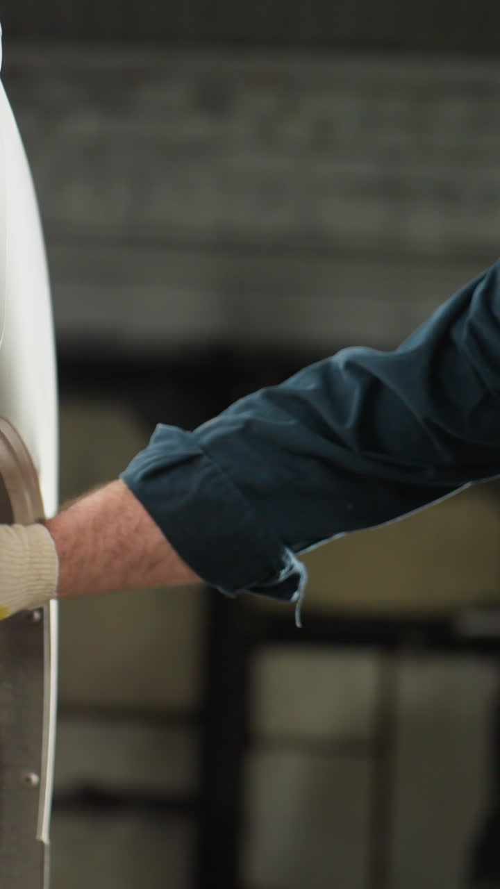 mecánico enfocado en uniforme azul inspecciona el neumático del coche con lámpara led mientras está arrodillado, mostrando un cuidado automotriz meticuloso en un taller