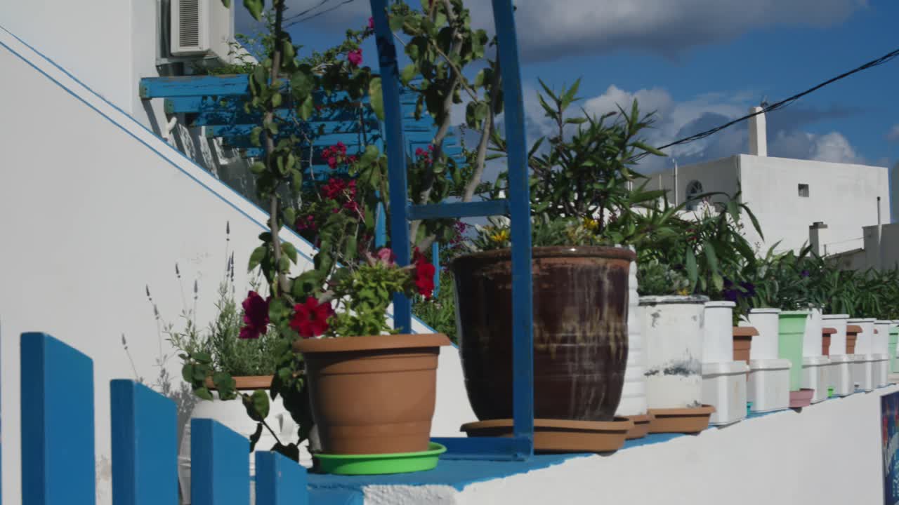 Two people walking by corner of village home in Santorini island, Greece