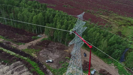 Toma-Giratoria-Superior-De-Los-Trabajadores-Que-Instalan-Un-Poste-De-Energía-Eléctrica-Usando-Una-Grúa-Roja-Durante-El-Día