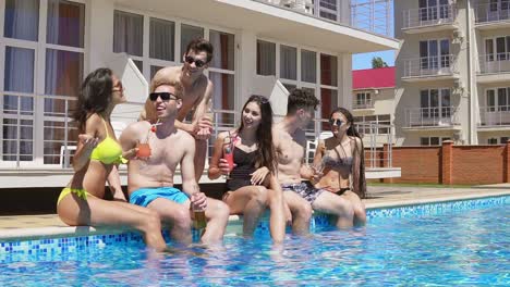 grupo feliz de jóvenes amigos pasando el rato con cócteles y charlando al lado de la piscina en el verano. fiesta en la piscina